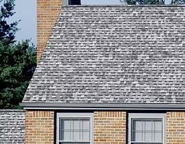 Brick house with gray and white shingle roof, chimney, windows.