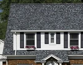 House with gray shingle roof, white siding, black shutters, and flower boxes under windows.