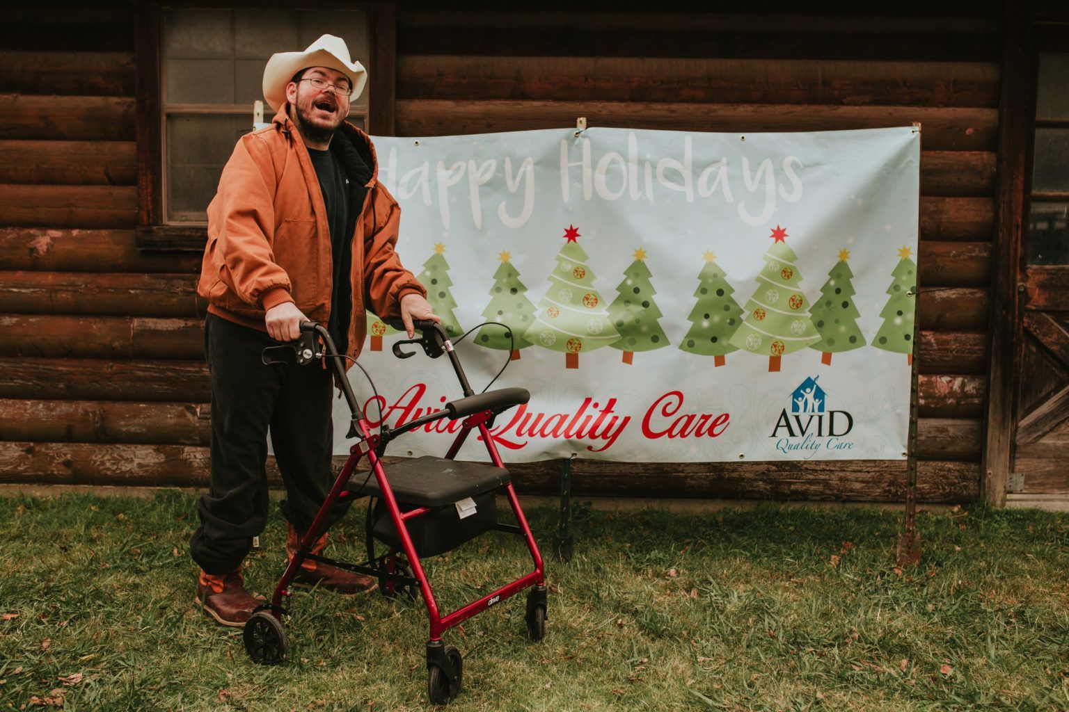 A man with a walker is standing in front of a sign that says happy holidays.