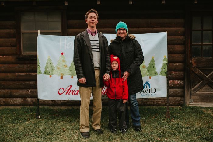 A family is posing for a picture in front of a log cabin.