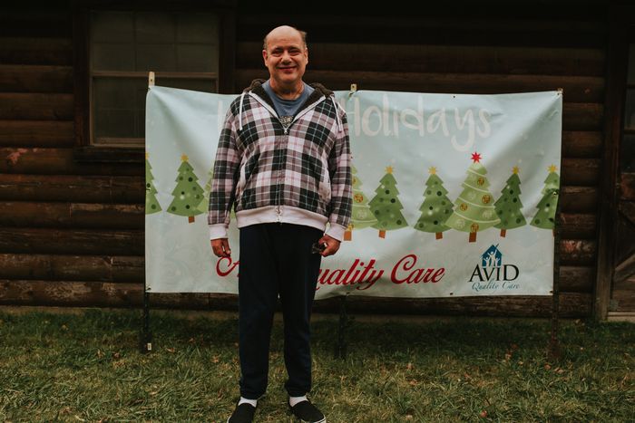 A man is standing in front of a sign with christmas trees on it.