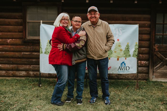 A group of people are posing for a picture in front of a log cabin.