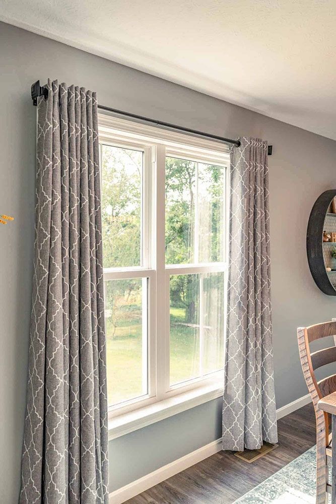 A living room with a large window and gray curtains.