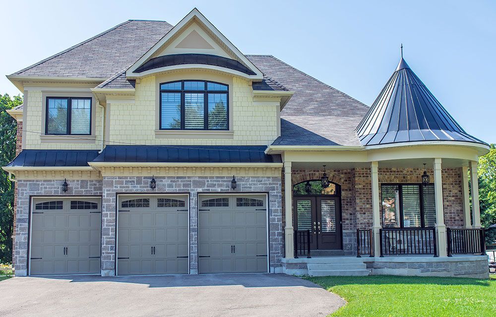 A large house with three garage doors and a porch.
