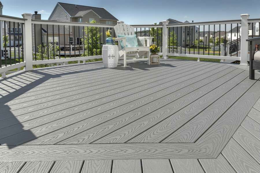 A gray deck with a white bench and chairs on it.