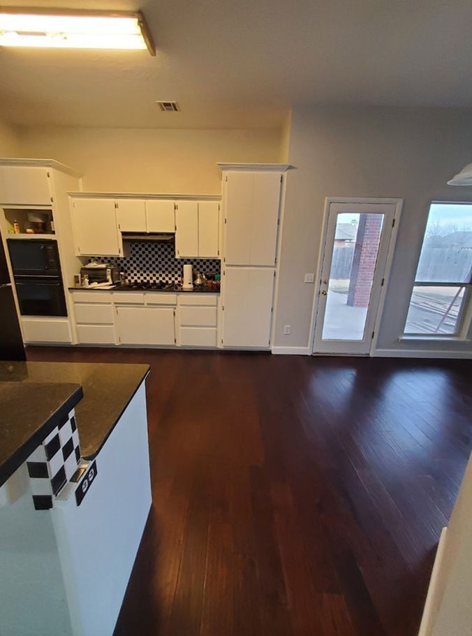 Kitchen with white cabinets, dark wood floors, and a black and white island.