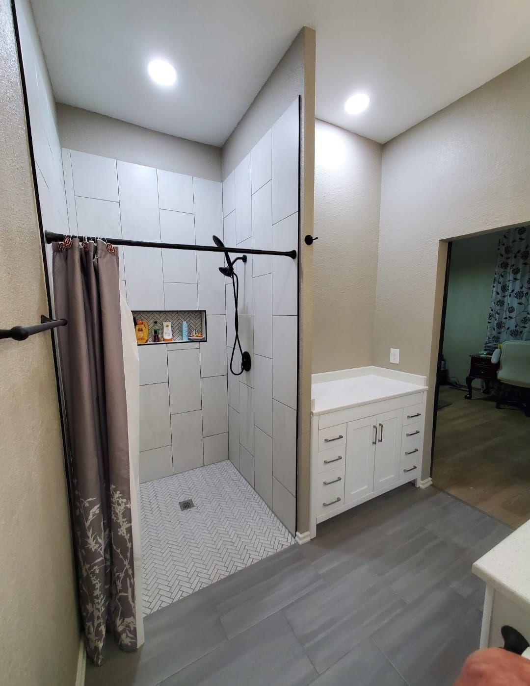 Modern bathroom with walk-in shower, white vanity, and gray floor tiles.