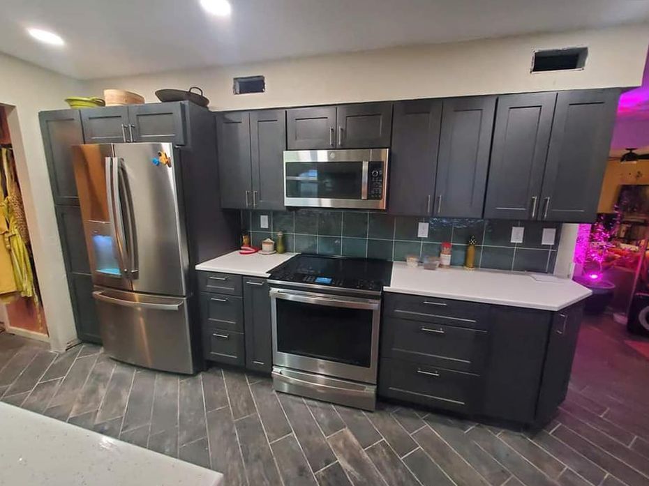 Kitchen with gray cabinets, stainless steel appliances, white countertops, and dark tile flooring.