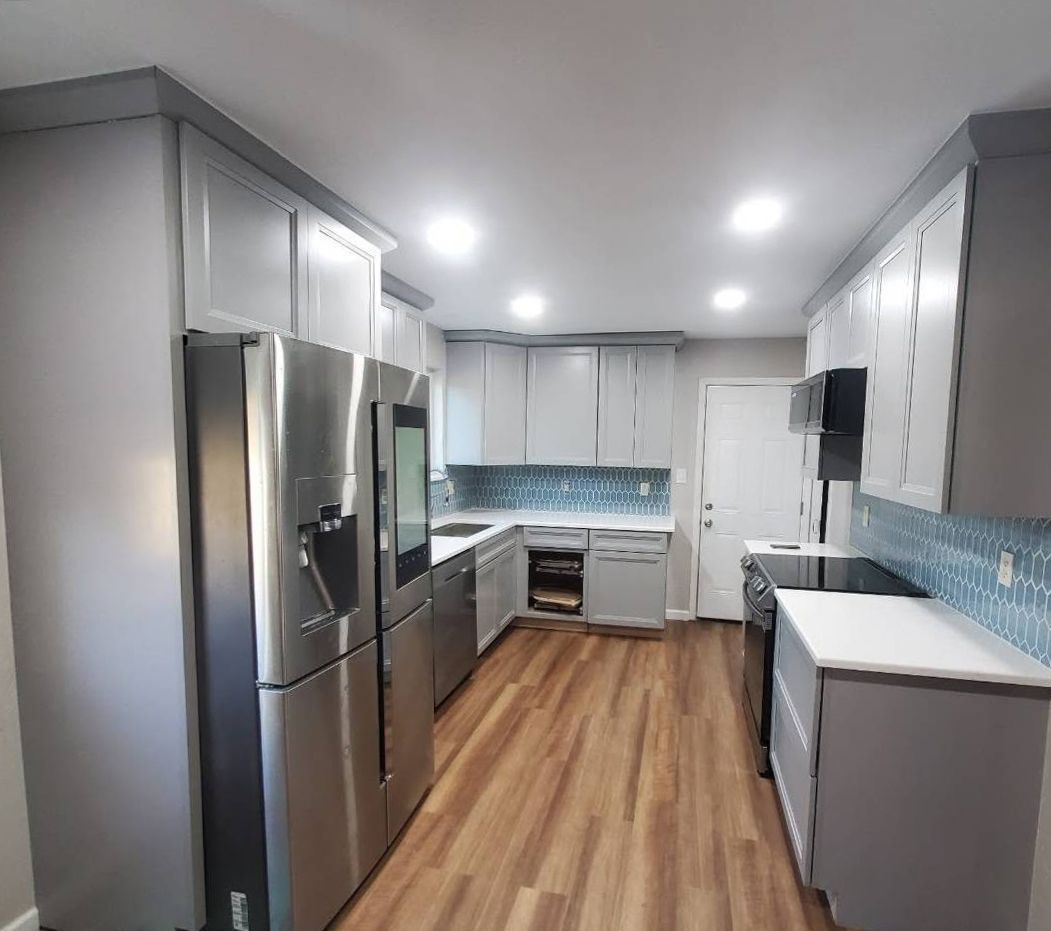 Kitchen with gray cabinets, stainless steel appliances, blue tile backsplash, and wood-look floor.