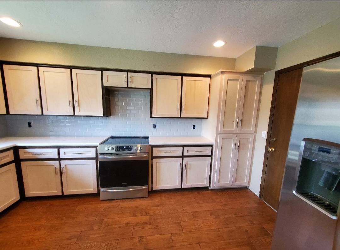 Kitchen with white cabinets, black trim, stainless steel stove, and wood floor.