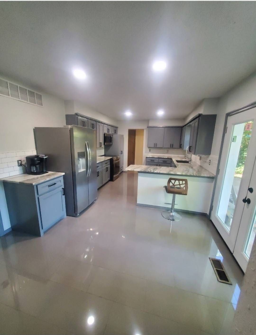 Modern gray kitchen with stainless steel appliances and white countertops.