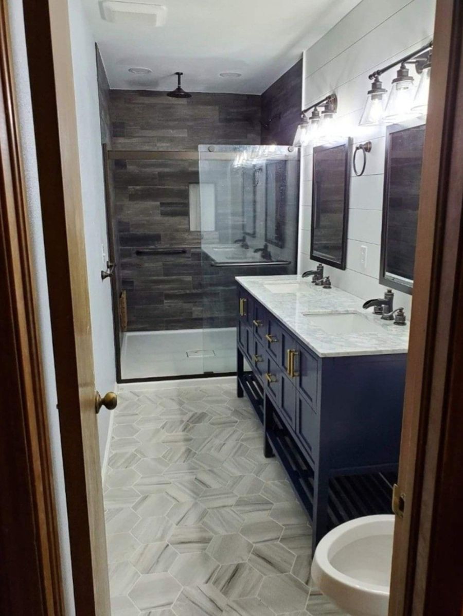 Bathroom with blue vanity, marble countertop, and wood-look tiled shower.