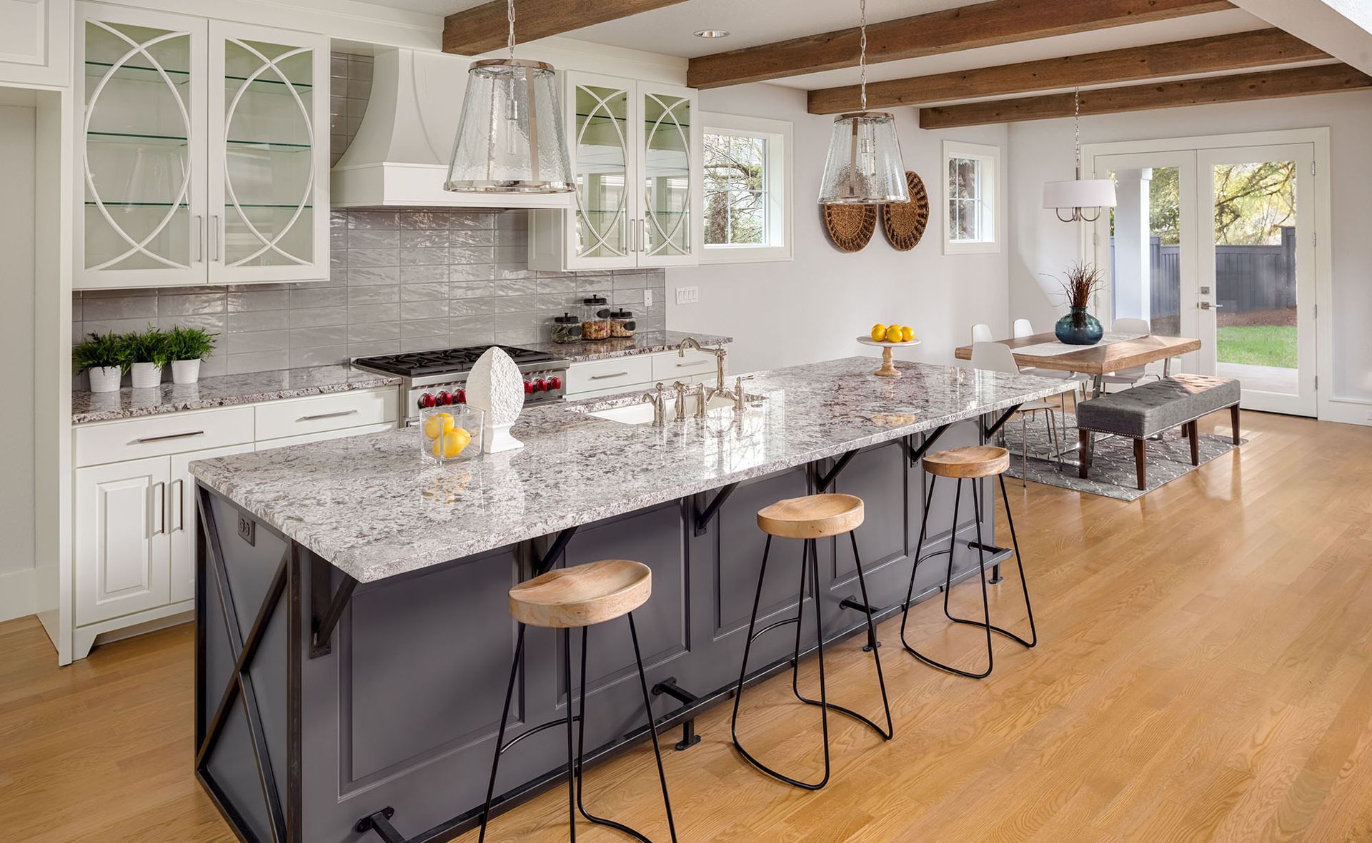 Modern kitchen with a large island, hardwood floors, white cabinets, and a granite countertop.