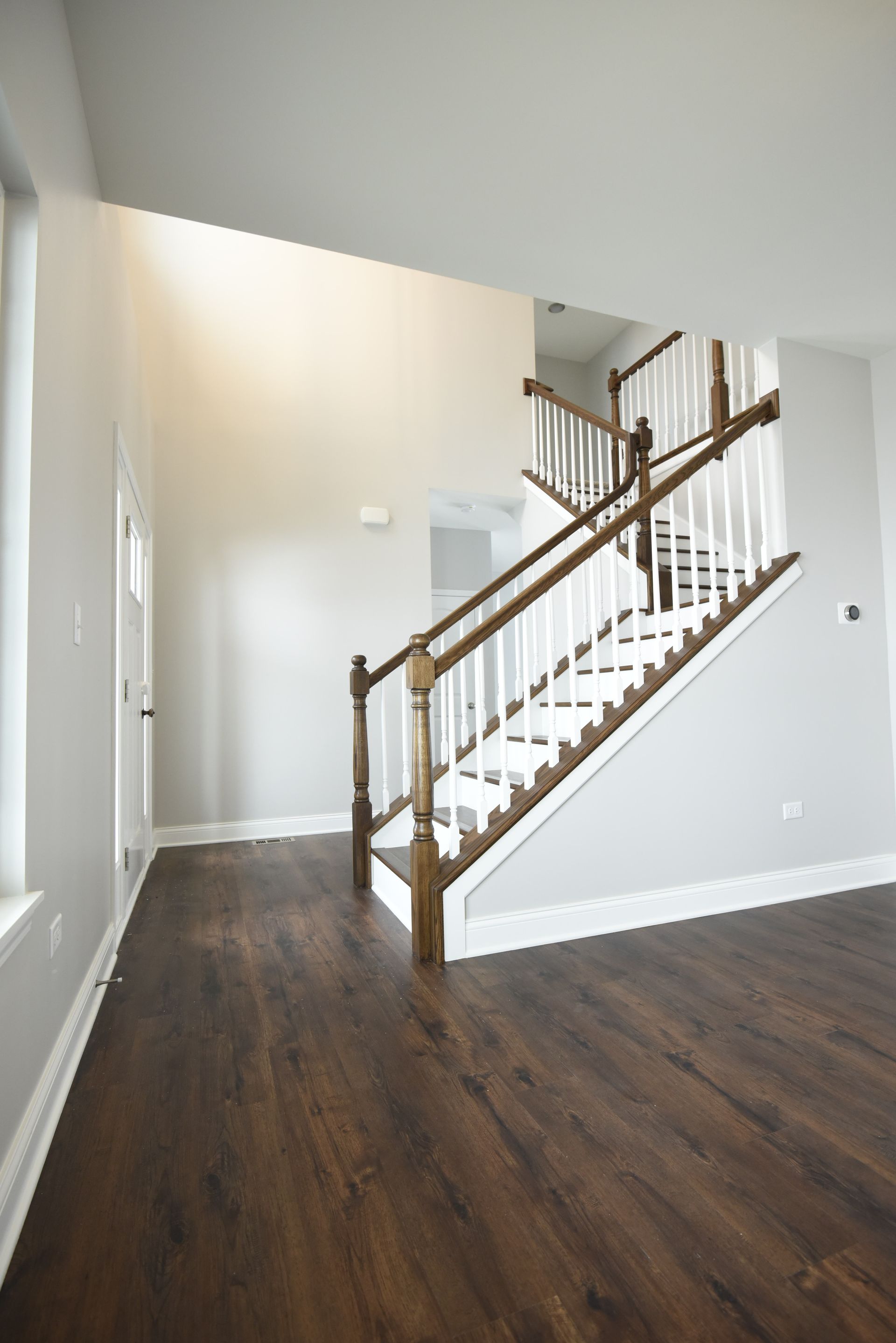 A kitchen and dining room in an empty house with hardwood floors.