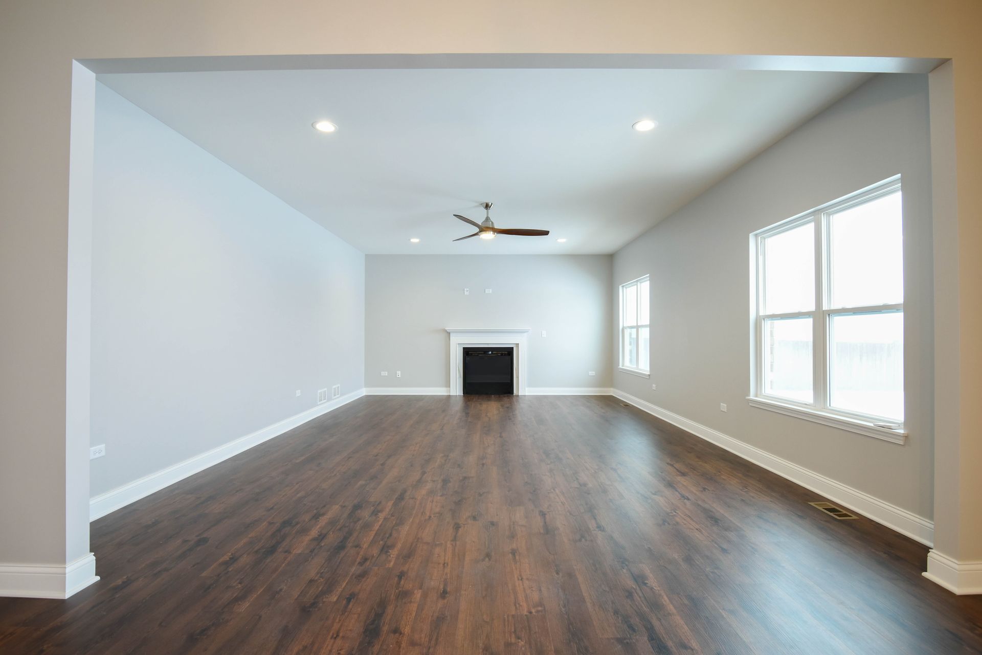 An empty bedroom with a vaulted ceiling and a ceiling fan.
