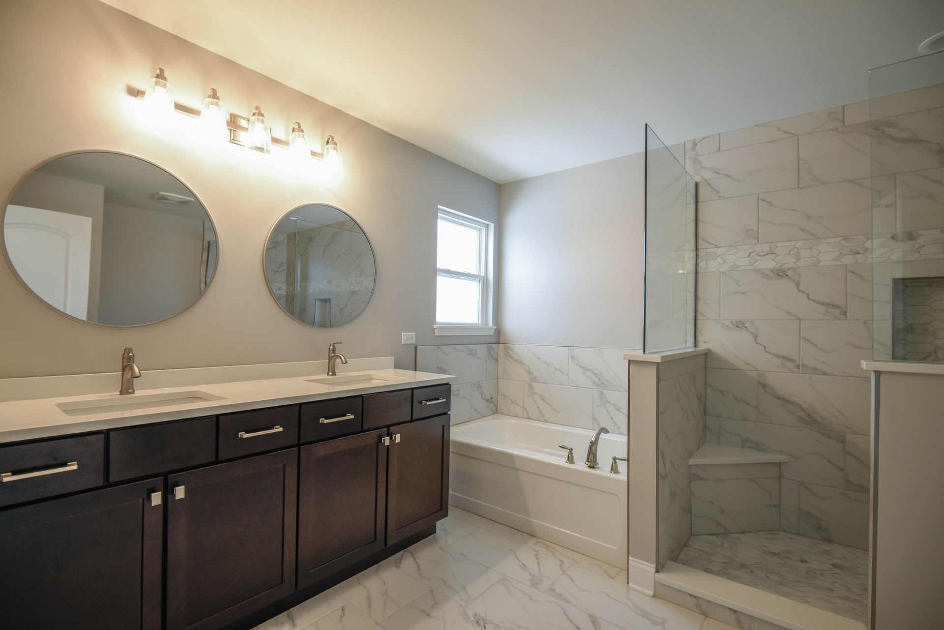 A bathroom with two sinks, a tub, and two mirrors.