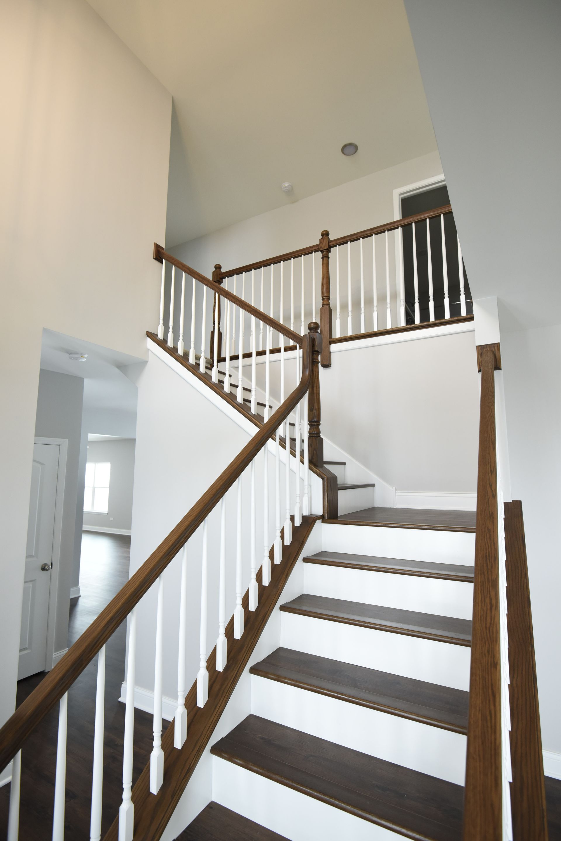 An empty living room with hardwood floors and stairs leading up to the second floor.