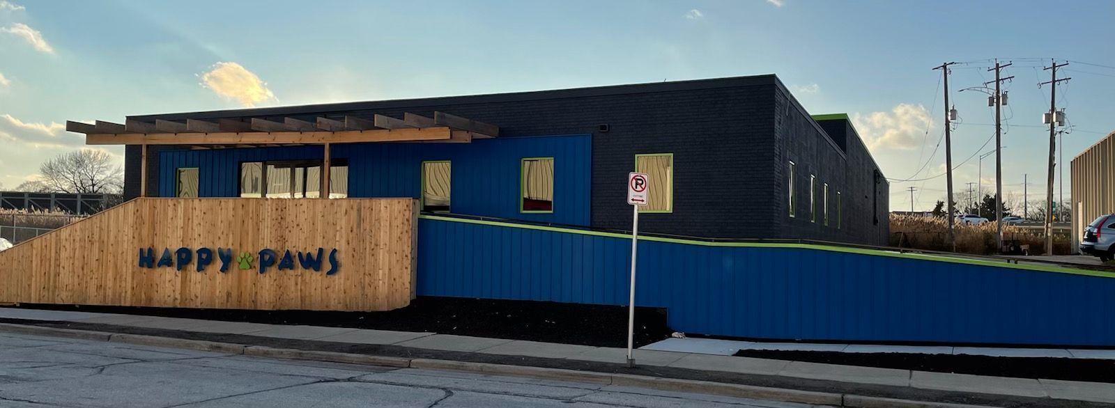 A building with a blue fence and a sign that says Happy Paws