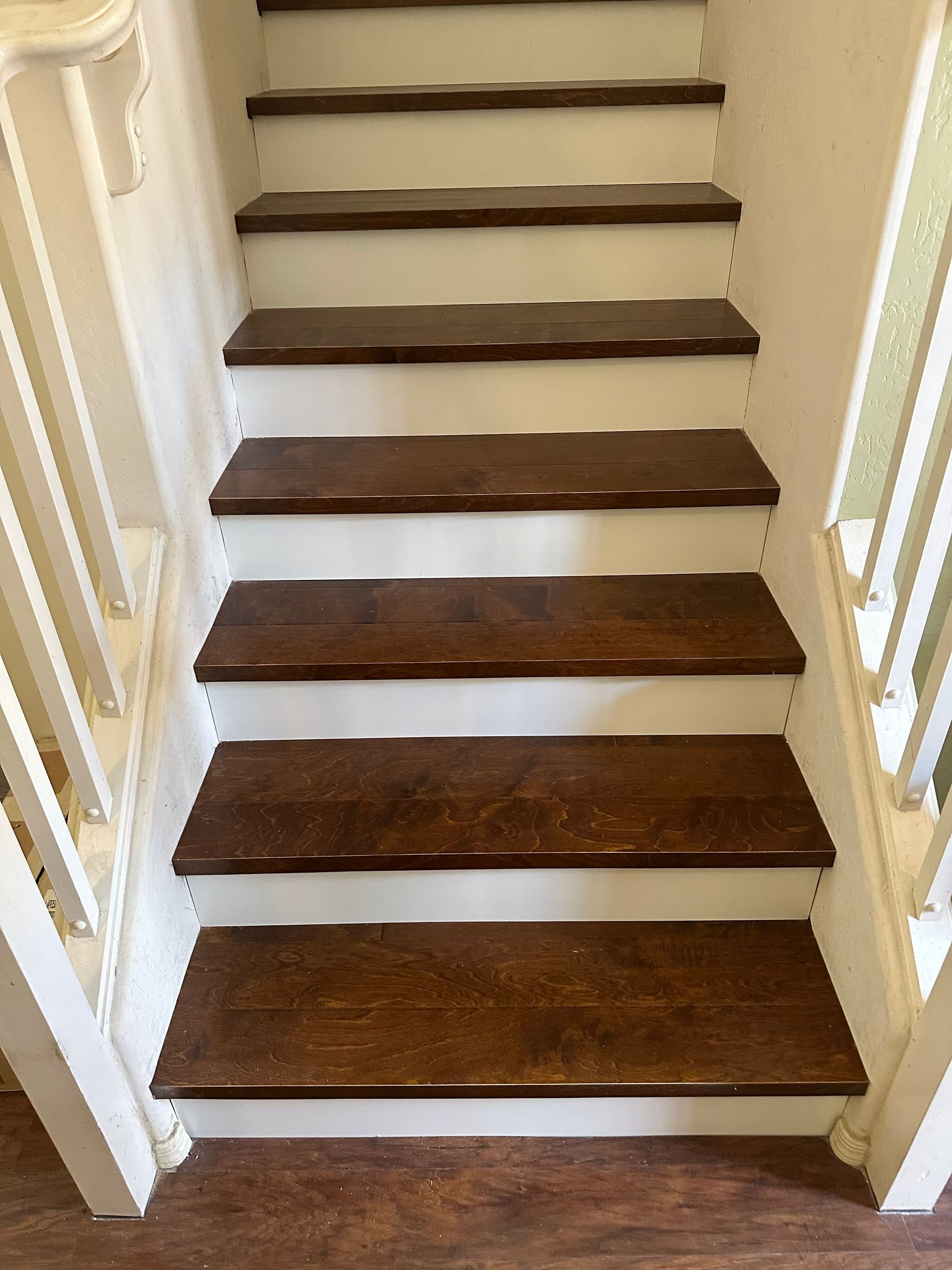 Indoor staircase with dark wooden steps, white trim, and cream-colored walls