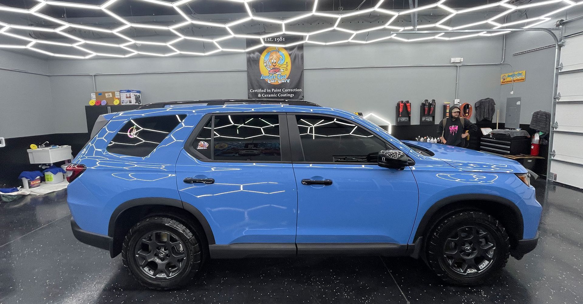 Blue SUV in a well-lit garage, with black wheels and tinted windows.