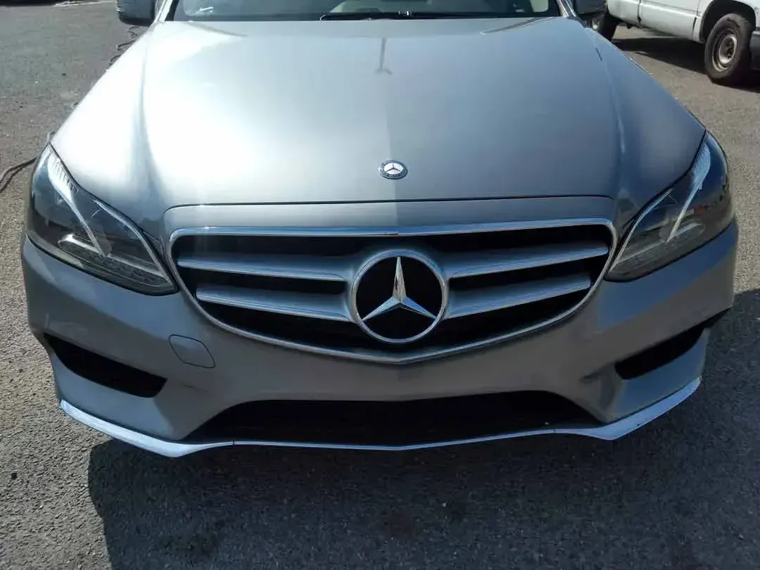 A silver mercedes benz is parked on the side of the road.