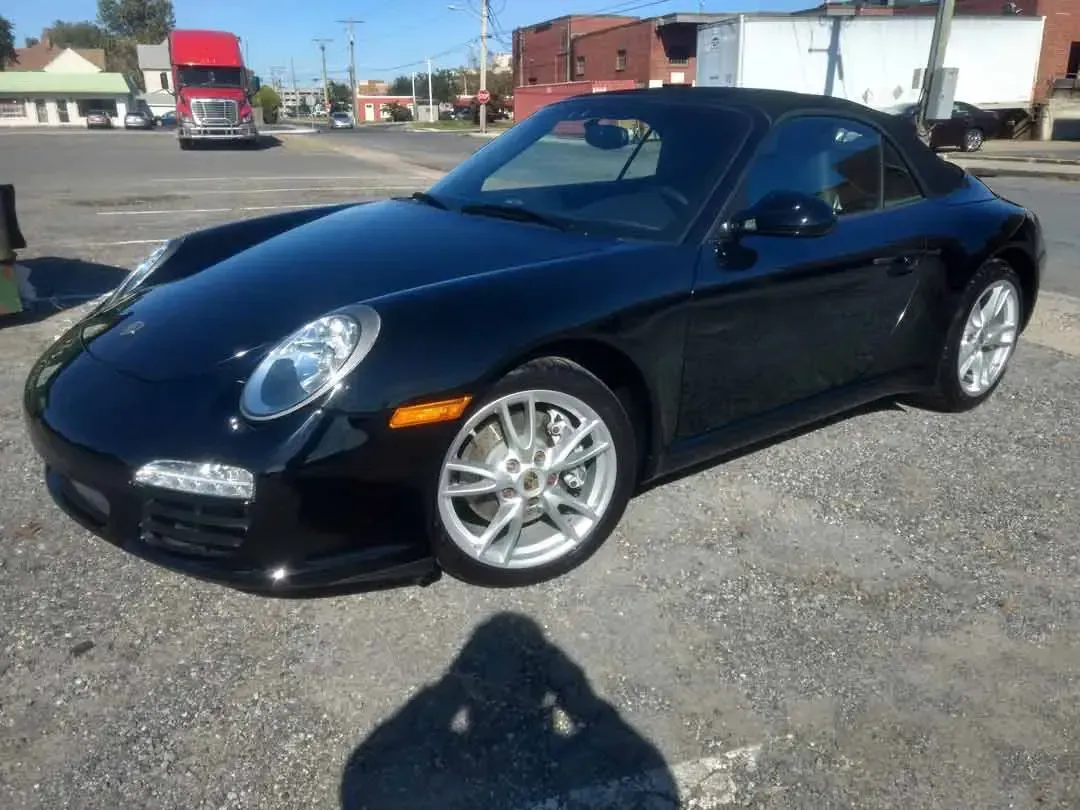 A black porsche 911 is parked in a parking lot