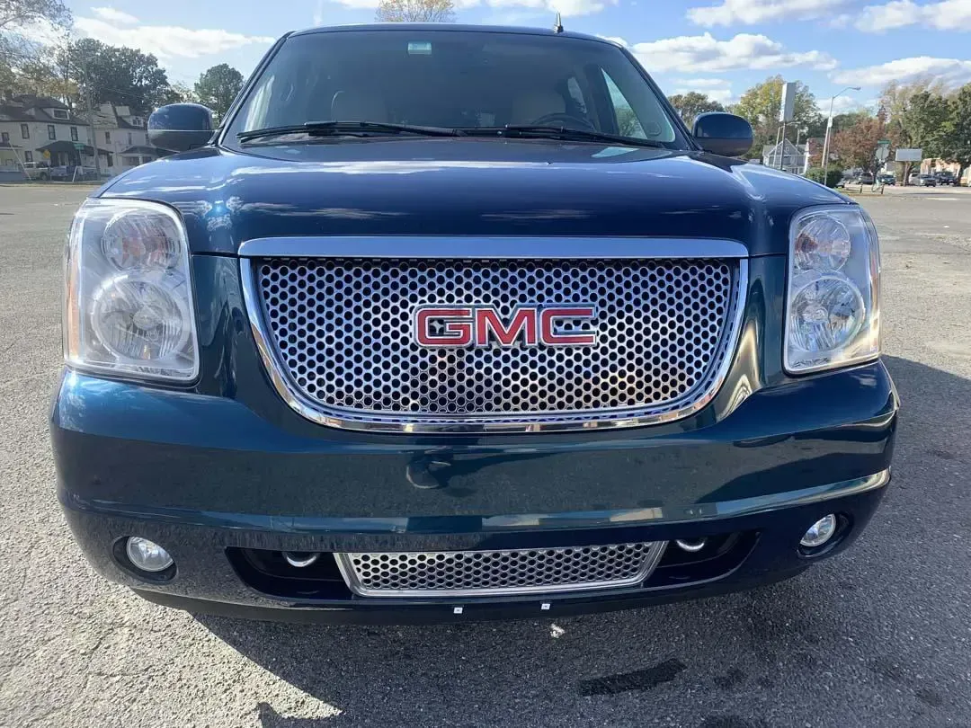 A blue gmc yukon is parked in a parking lot.