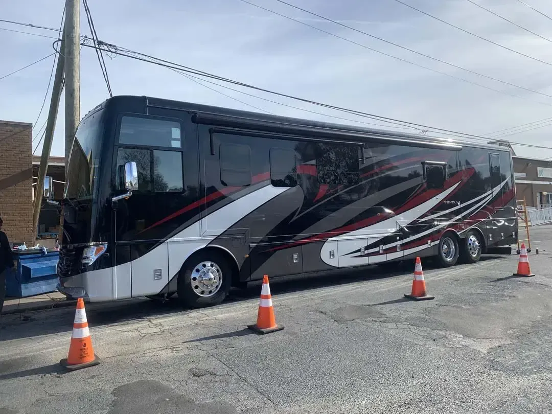 A large bus is parked on the side of the road next to traffic cones.