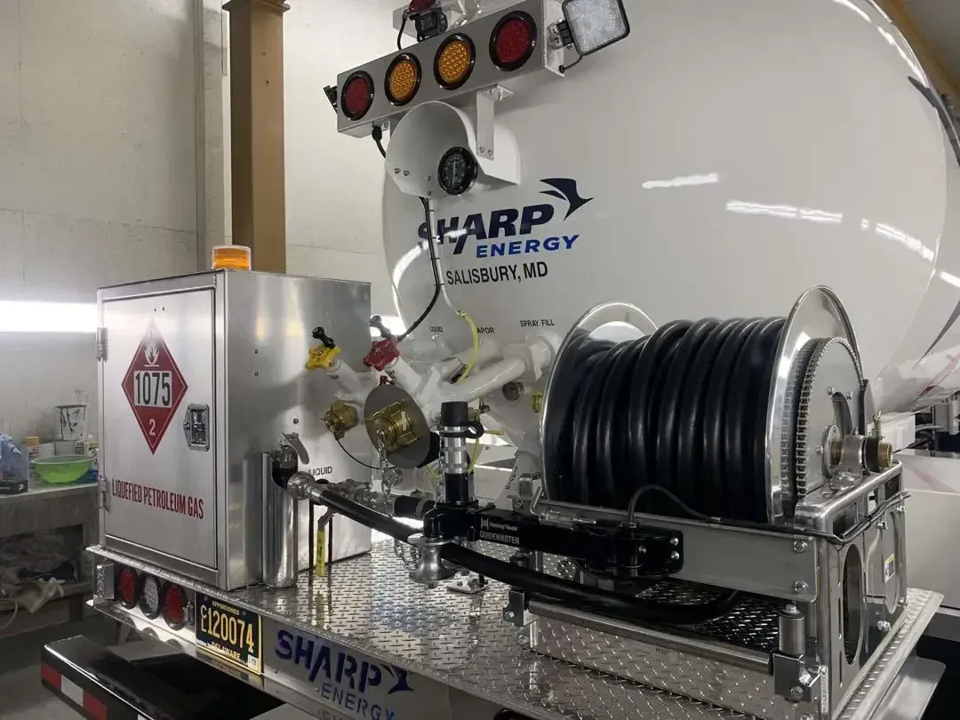 A white truck with a hose attached to it is parked in a garage.