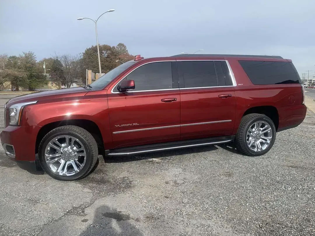 A red gmc yukon is parked in a gravel lot.