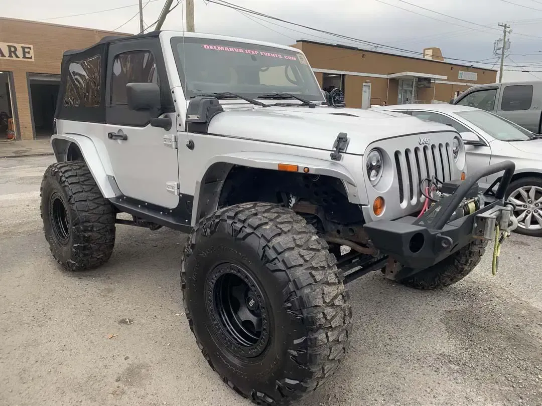 A white jeep wrangler is parked in front of a building.