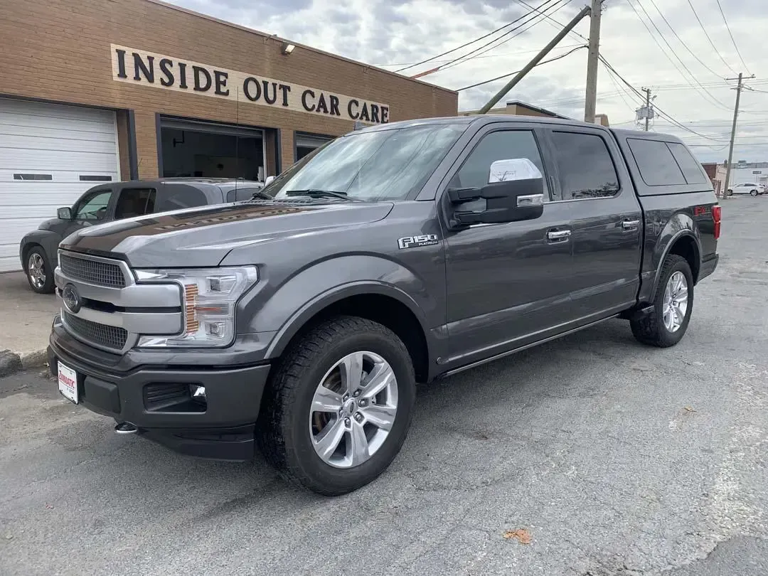 A gray ford f150 is parked in front of a building.