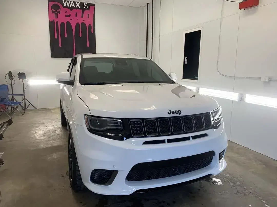A white jeep grand cherokee is parked in a garage.