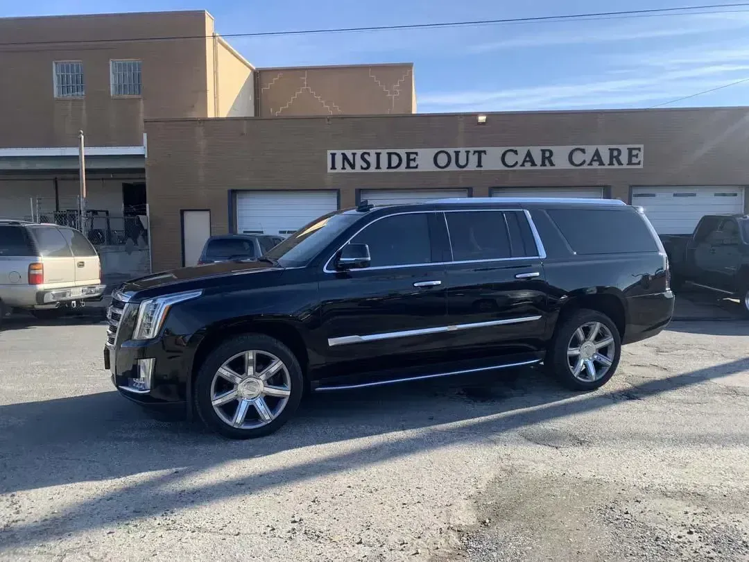A black suv is parked in front of a building that says inside out car care.
