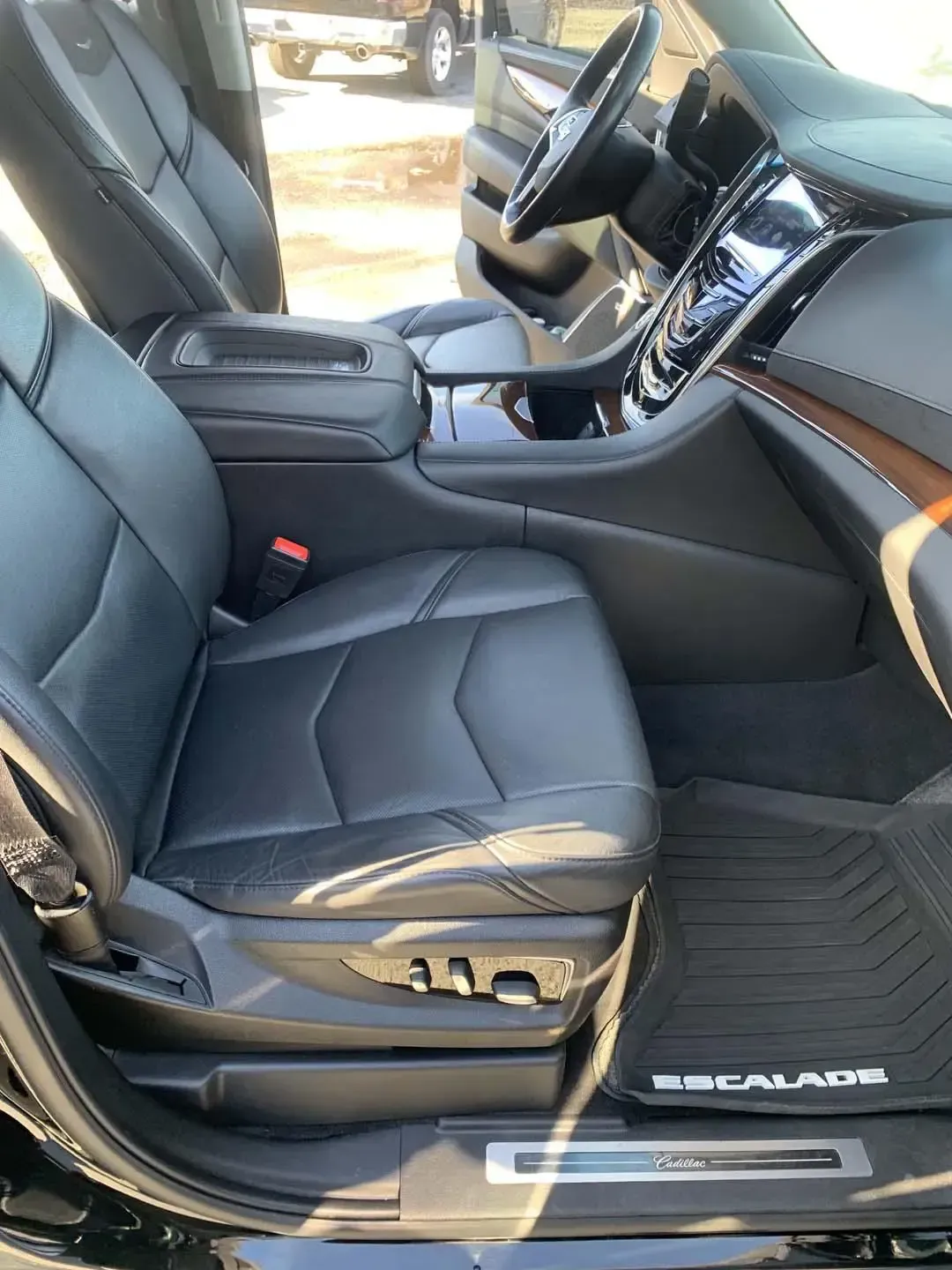 The interior of a black cadillac escalade with the door open.