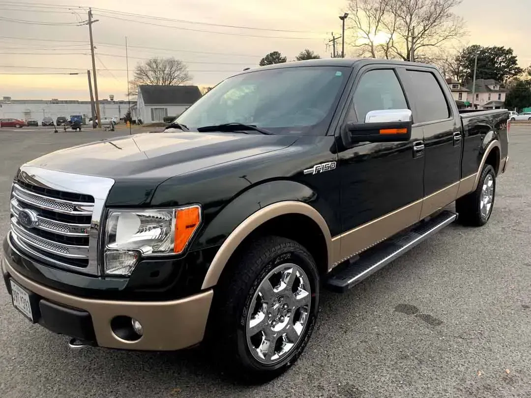 A black and gold ford f150 pickup truck is parked in a parking lot.