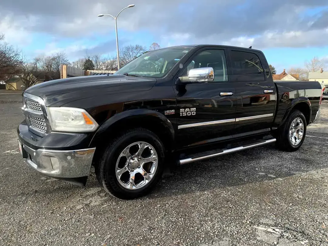 A black dodge ram truck is parked in a gravel lot.