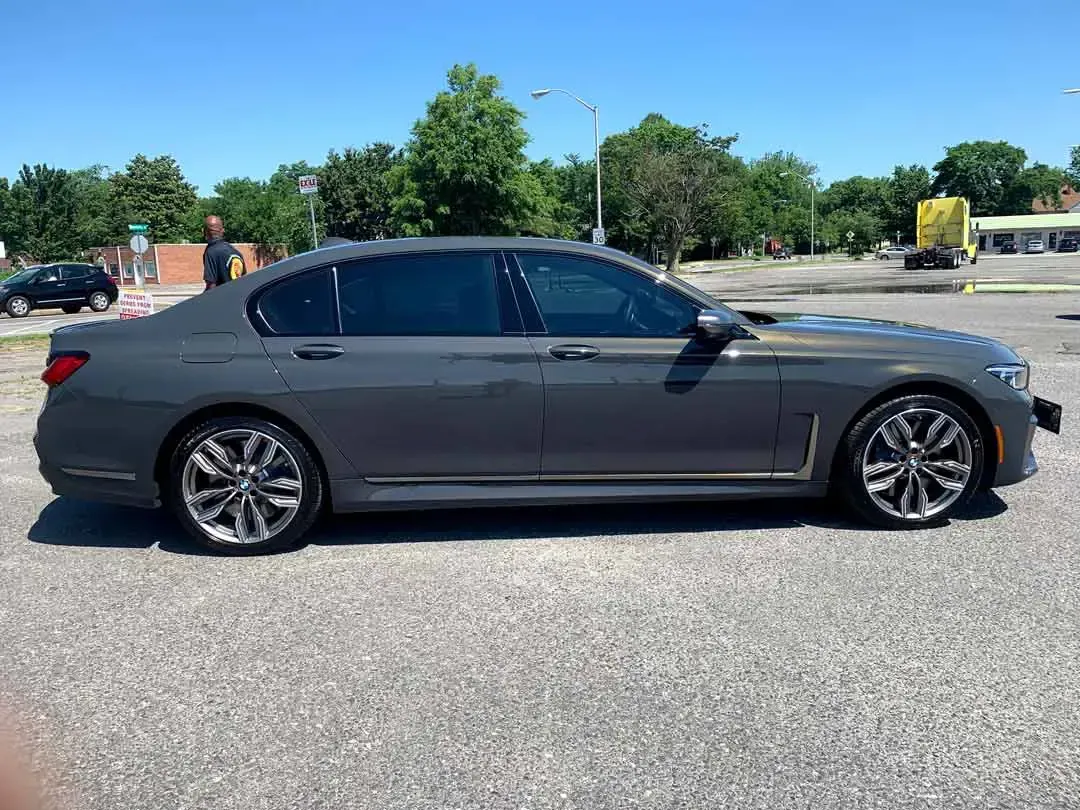 A gray bmw 7 series is parked in a parking lot.