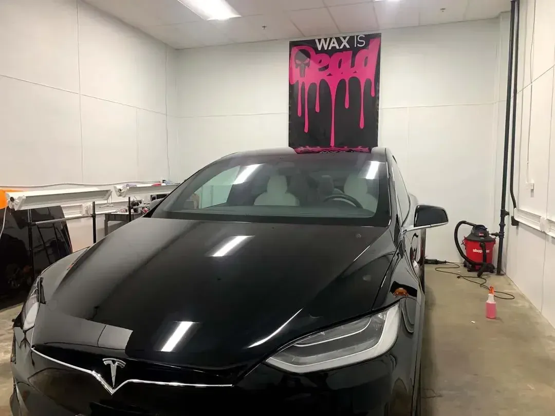 A black tesla model x is parked in a garage.