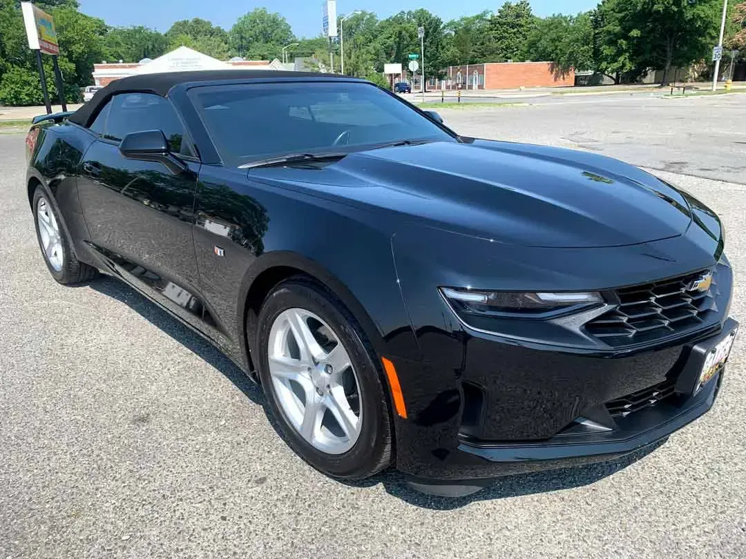 A black chevrolet camaro convertible is parked in a parking lot.