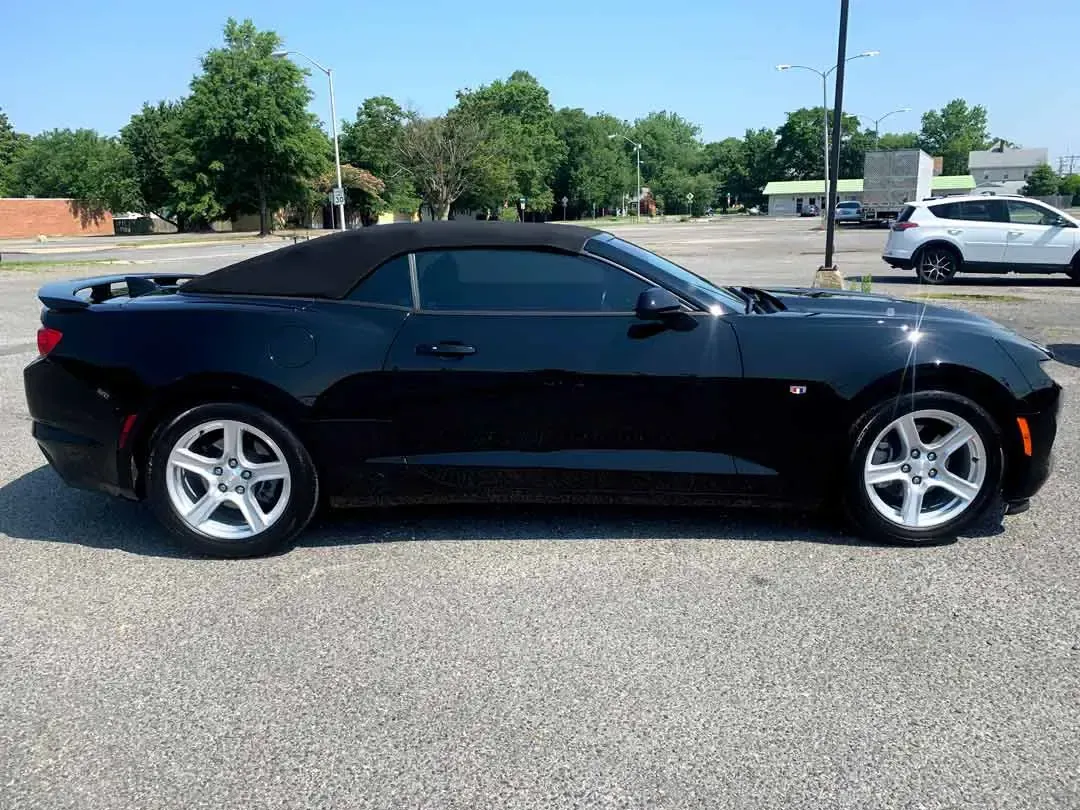 A black convertible car is parked in a parking lot.