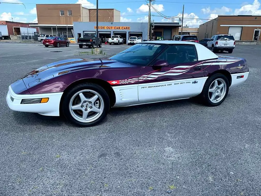 A purple and white corvette is parked in a parking lot.