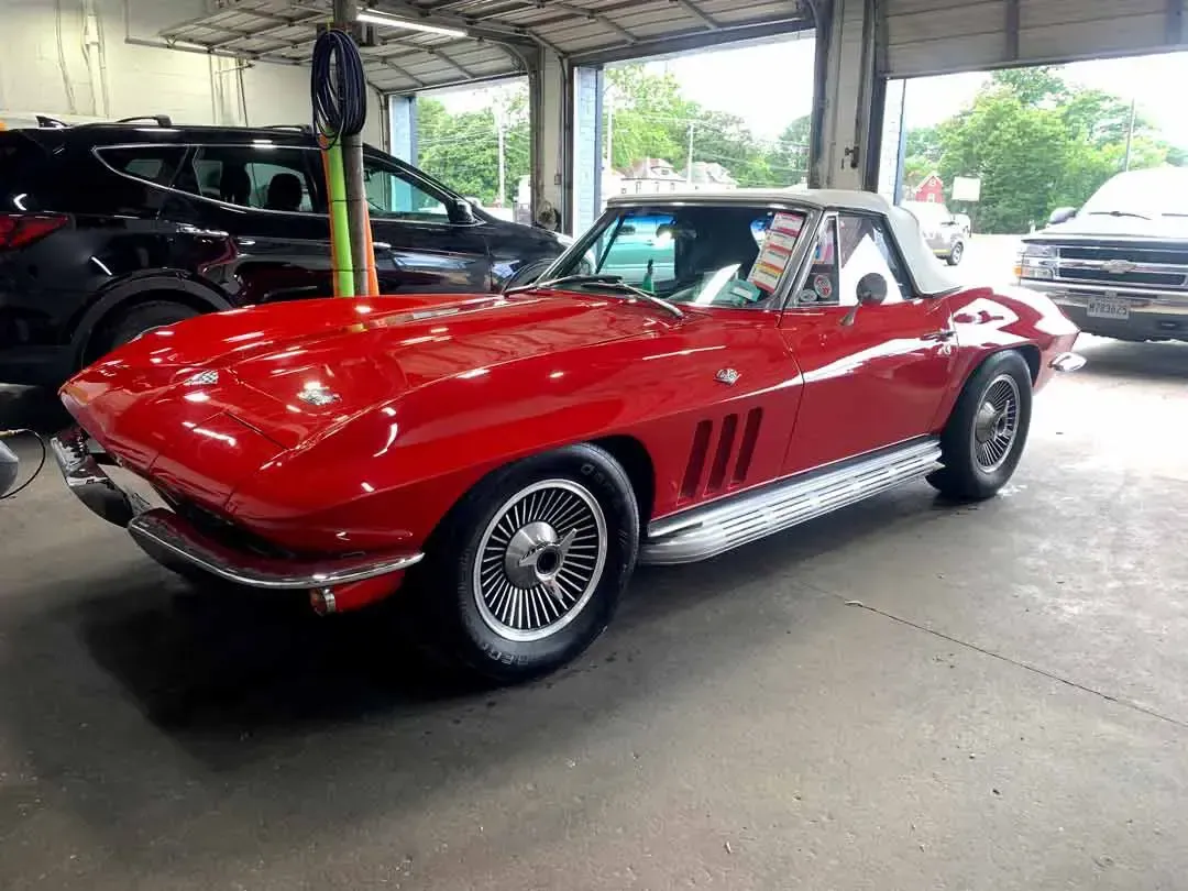 A red corvette convertible is parked in a garage.