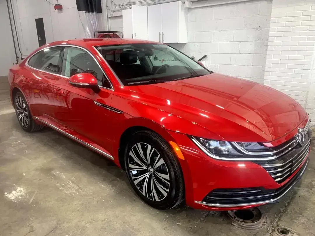 A red volkswagen arteon is parked in a garage.