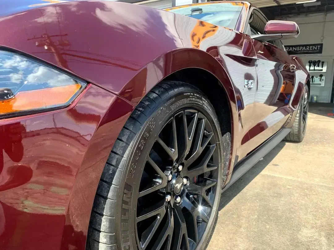 A red ford mustang is parked in a parking lot.