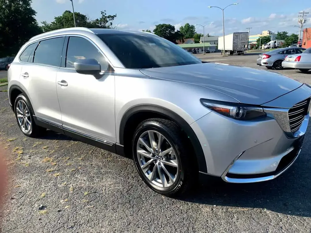 A silver mazda cx 9 is parked in a parking lot.