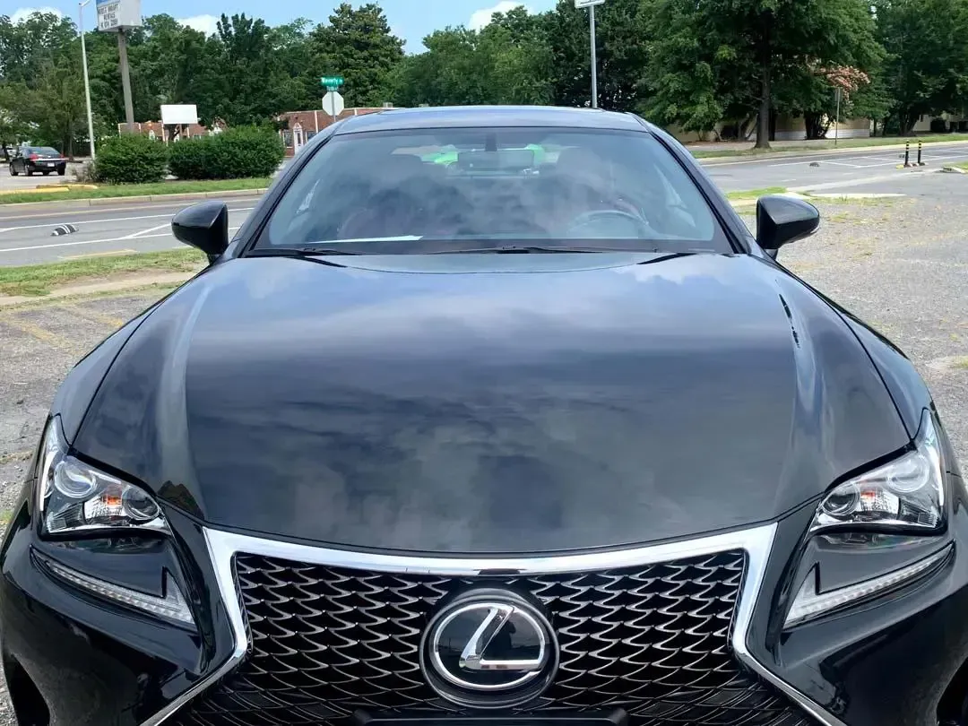 A black lexus is parked in a parking lot.