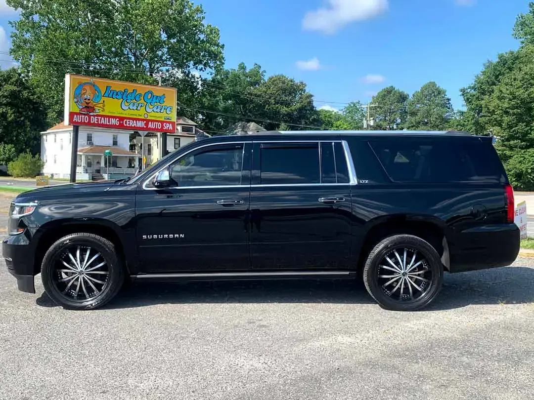 A black suv is parked in front of a yellow sign.