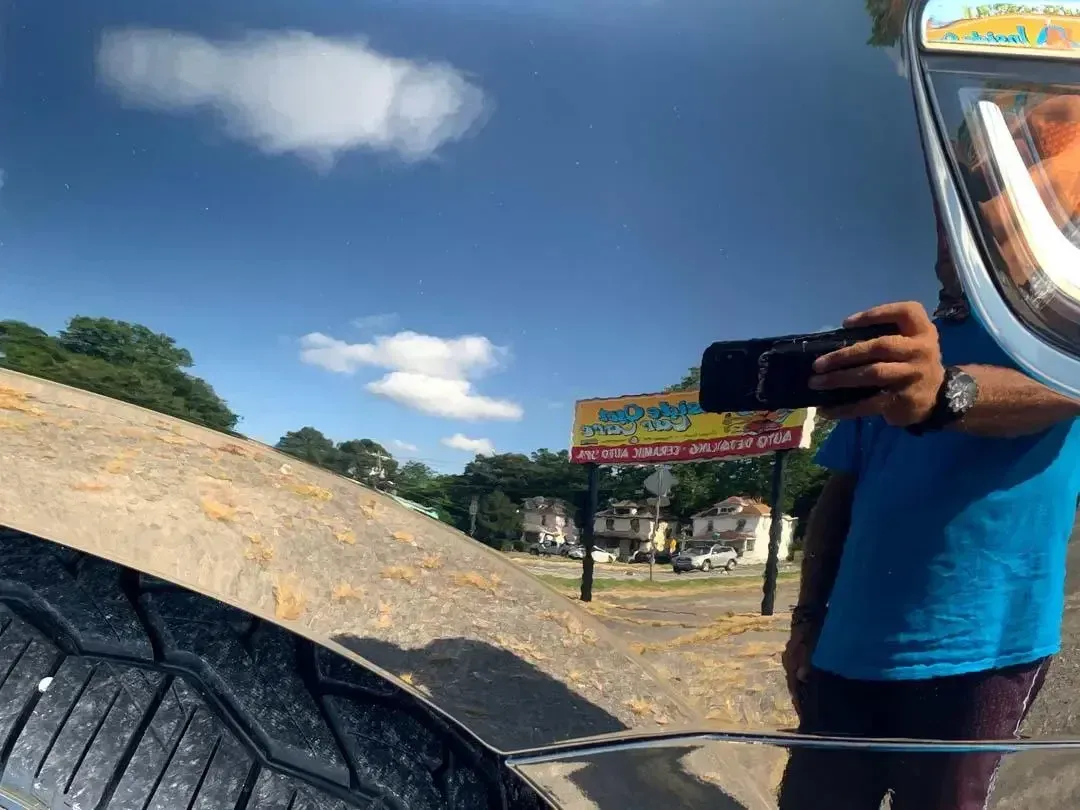 A man is taking a picture of himself in the rear view mirror of a car.