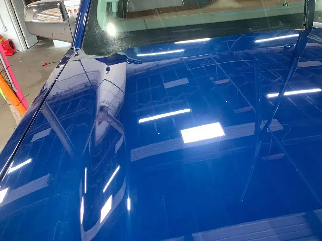 A close up of a blue car hood in a garage.